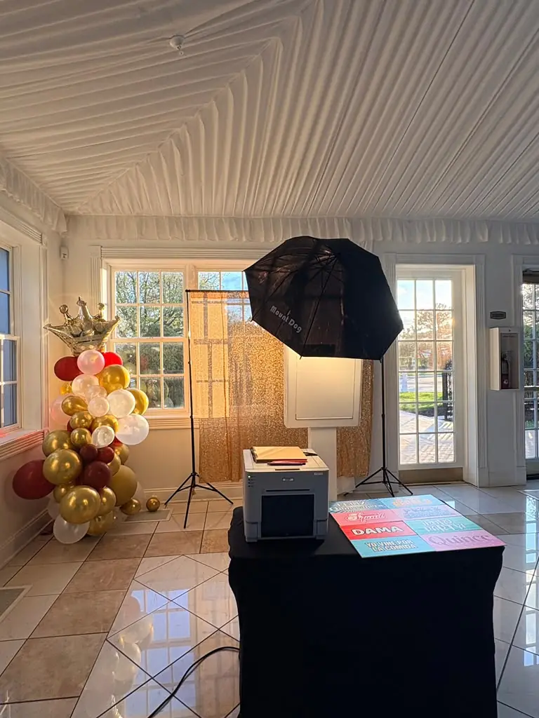 Booth with gold sequin backdrop and balloon tower by the windows